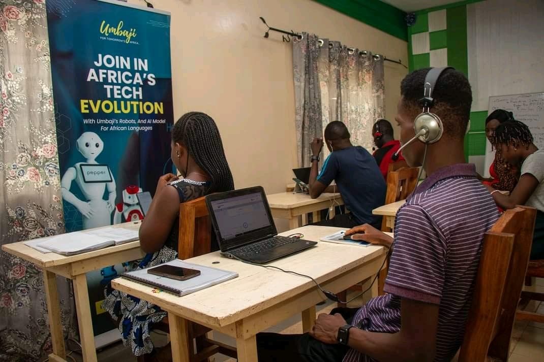 Session de travail Umbaji devant un kakémono « Join in Africa’s tech evolution », participants au casque devant leurs ordinateurs